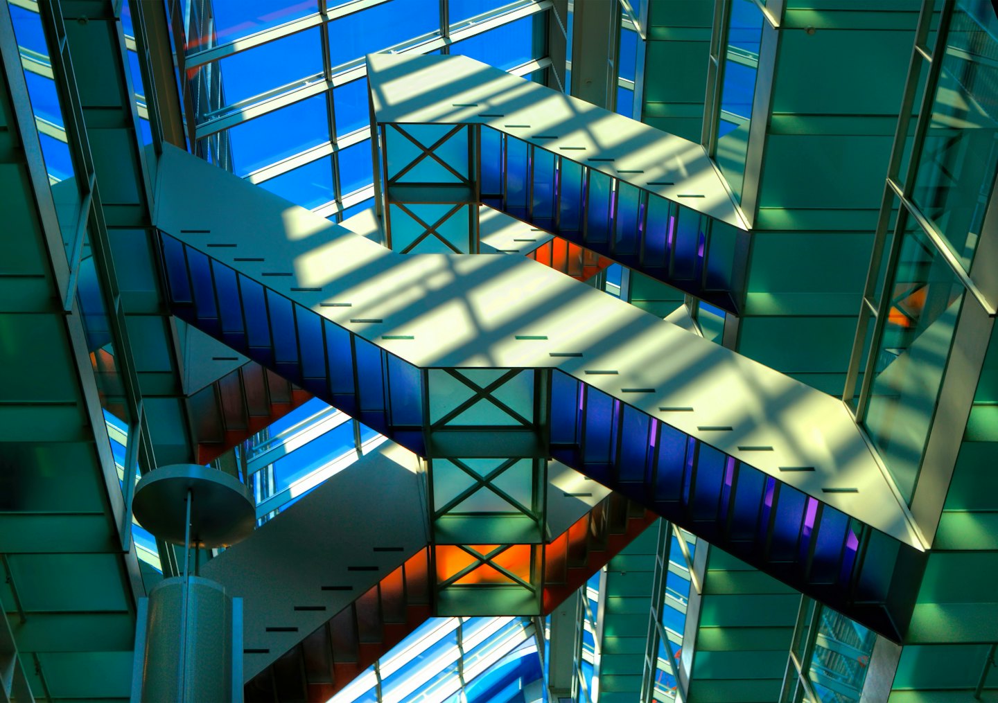 Geometrische Glaspaneele und tragende Balken an einem modernen Gebäude.