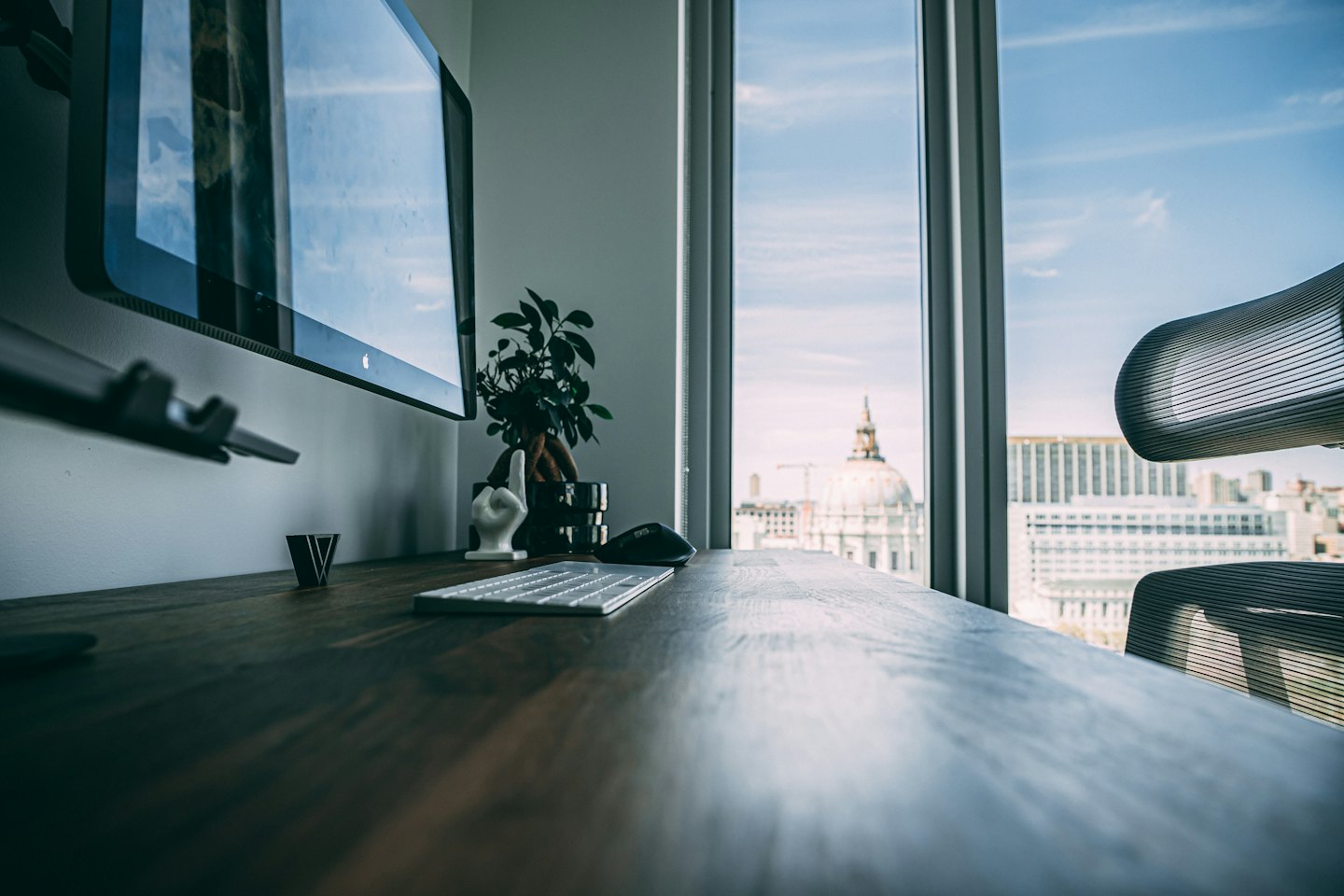 Moderner Bürotisch mit Computerausrüstung und Blick auf eine Stadtkulisse.