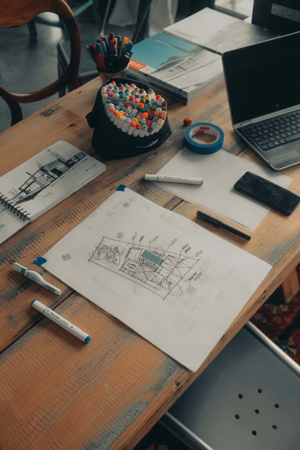 Architekturskizzen und bunte Marker auf einem belebten Schreibtisch.