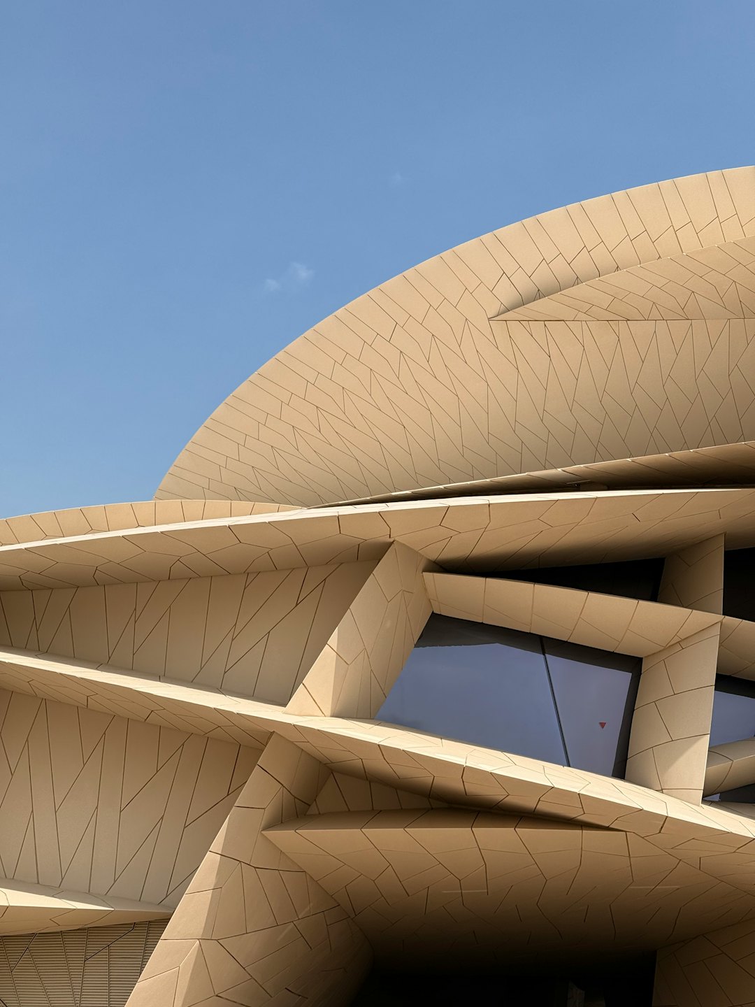 Modernes Gebäude mit geometrischen beigen Paneelen und reflektierenden Fenstern.